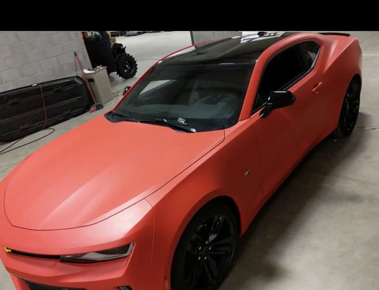 A red car parked in a garage with its door open.